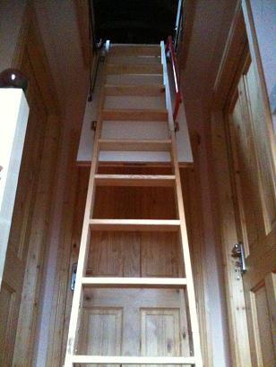 Picture of a very cool wooden ladder stretching up to the large opening for the attick.