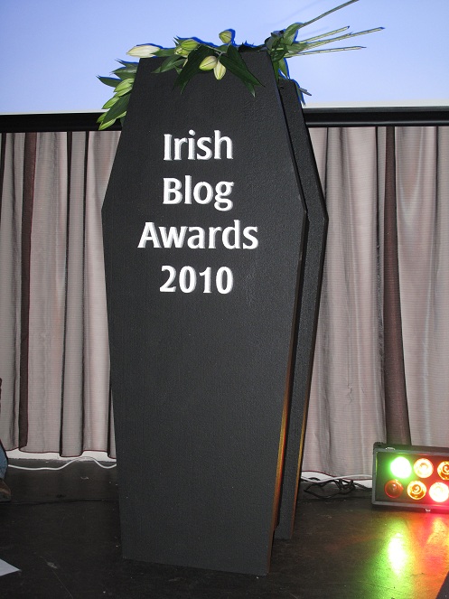 The Irish Blog awards Coffin standing up right with lillies around it.