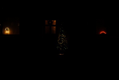 Looking toward the house at the tree in the porch the angel in the left window and the electric candle things in the right one.
