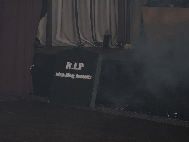 The Coffin is surrounded in fog generated by a smoke machine. the words written on the top of the coffin are: RIP IBA