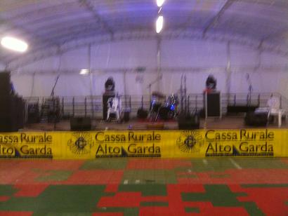 A picture of a reasonably large stage with mike stands, a few instruments and lights set up.